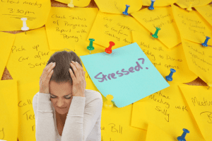 Woman holding head in hands with yellow to do post it notes in background